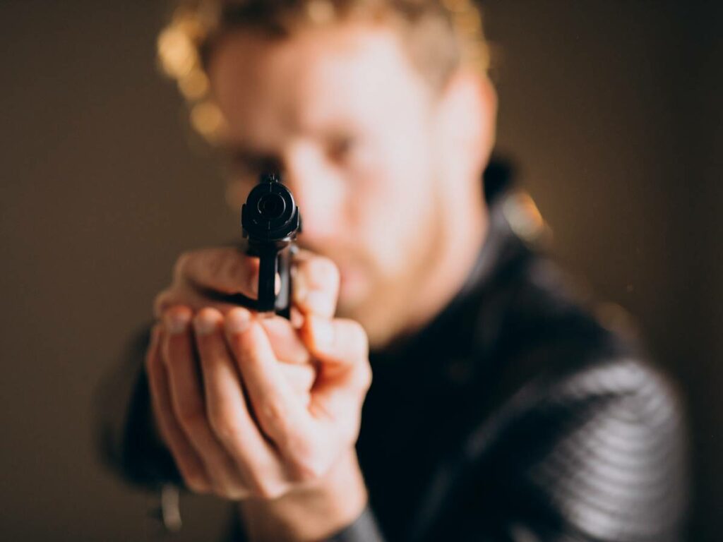 Handsome man actor posing in studio with weapon