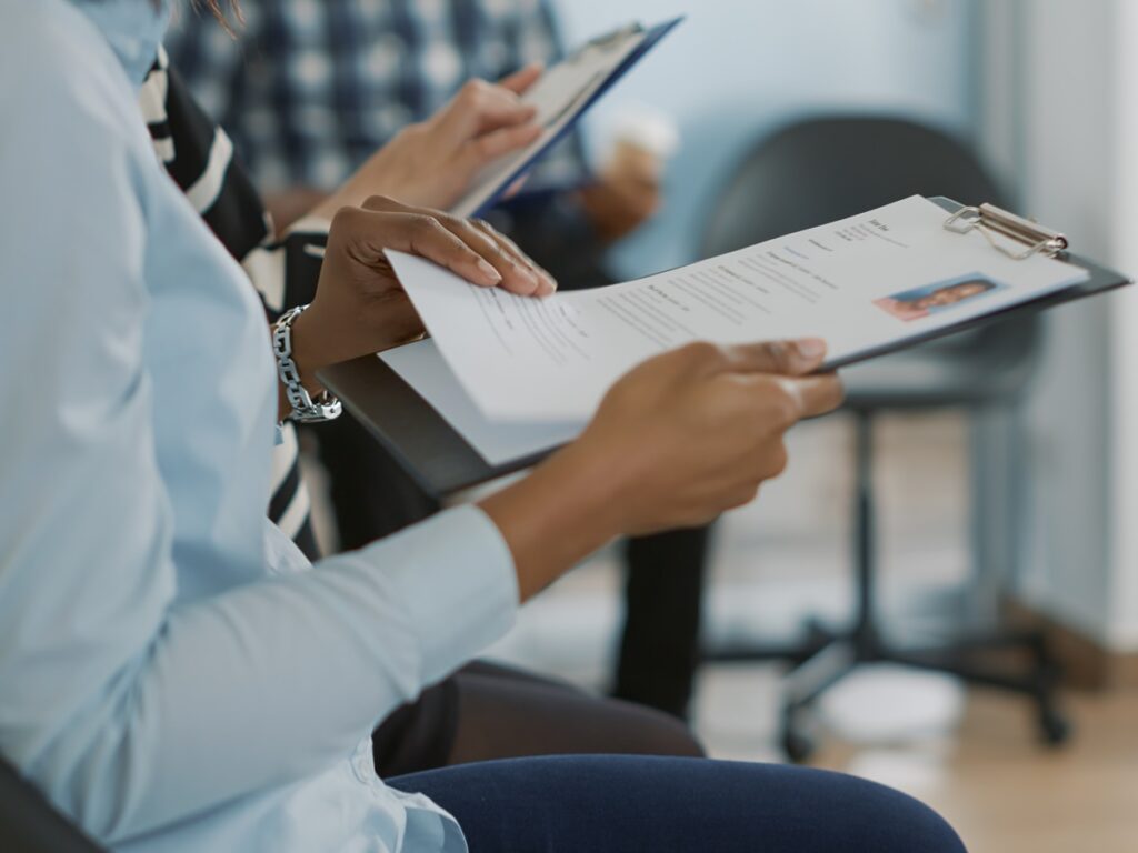 Female candidate sitting in queue and receiving cv files, waiting to start job interview about career opportunity. Woman getting ready to attend recruitment meeting with HR employee.