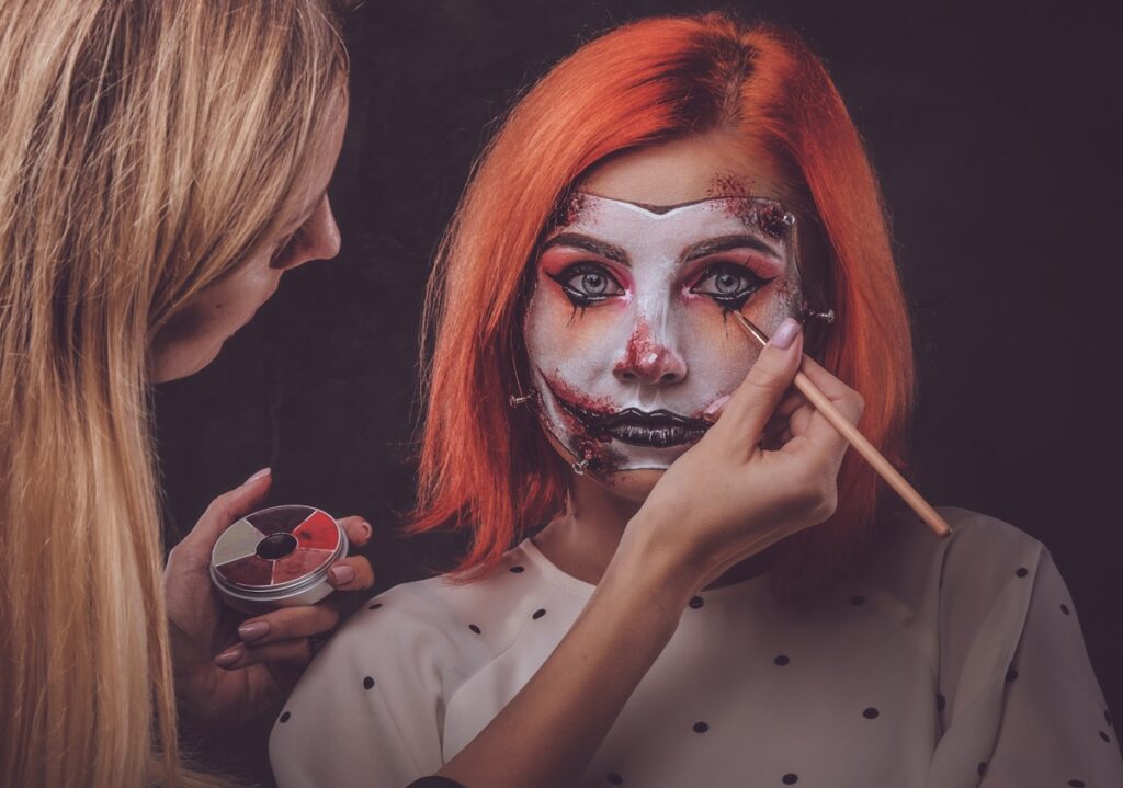 Talented makeup artist is creating special scary Halloween art on woman's face.