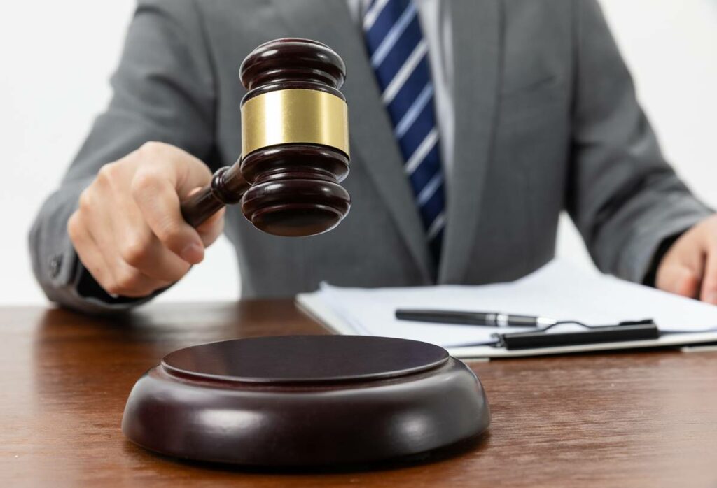 A closeup shot of a person holding a gavel on the table