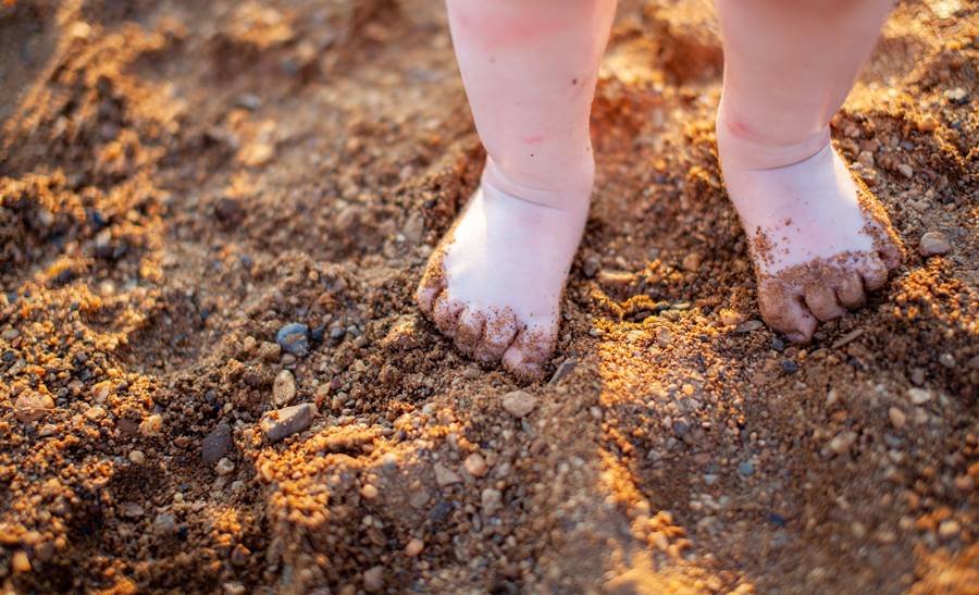 Children's bare feet in summer on a golden sandy beach close-up. The concept of child safety. The concept of recreation with children.