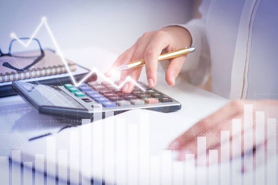 Accountant calculating profit with financial analysis graphs. Notebook, glasses and calculator lying on desk. Accountancy concept. Cropped view.