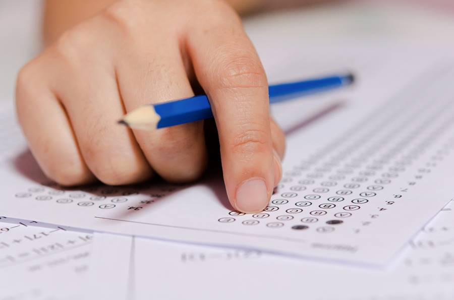 Students hand holding pencil writing selected choice on answer sheets and Mathematics question sheets. students testing doing examination. school exam