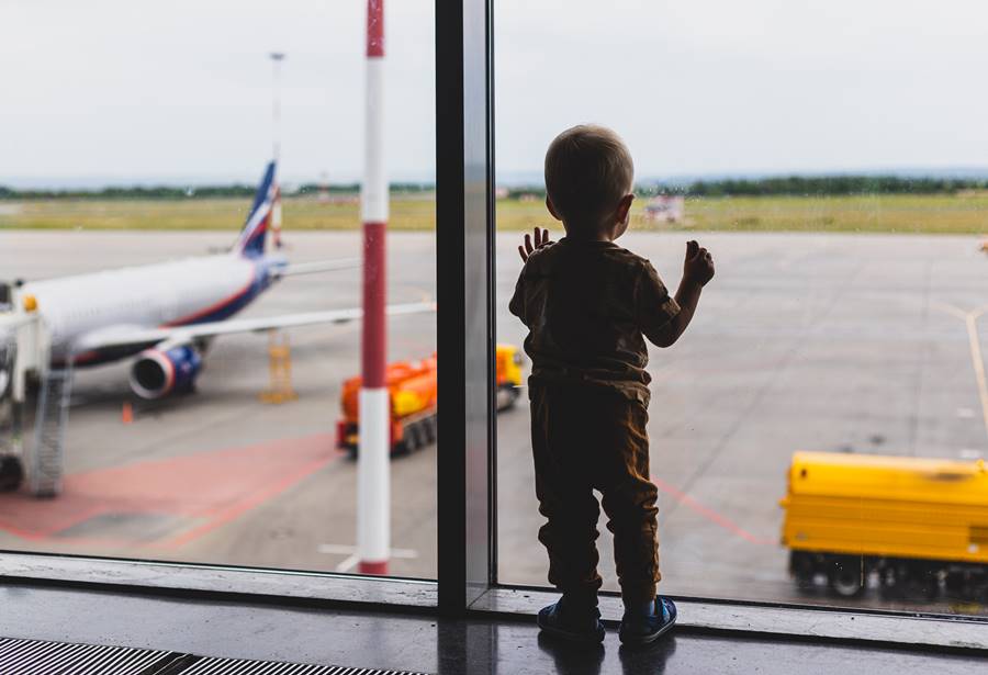 toddler-blond-boy-looks-planes-through-glass-large-window-airport