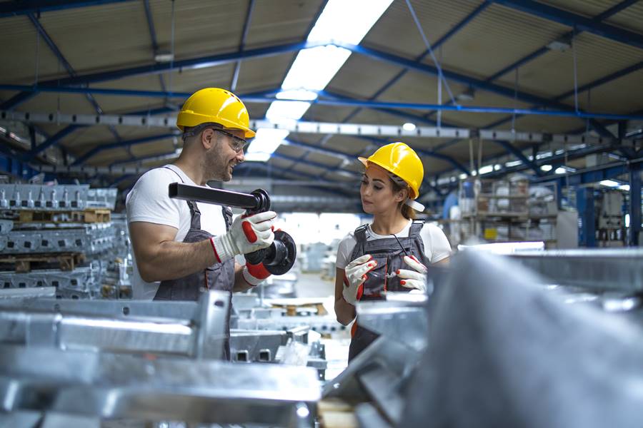 Workers checking quality of metal parts manufactured in factory.