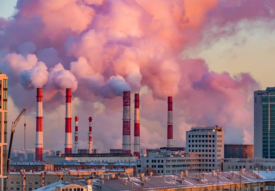 Steam or smoke comes from the pipes. Combined heat and power plant in the city. Landscape at sunset or dawn.