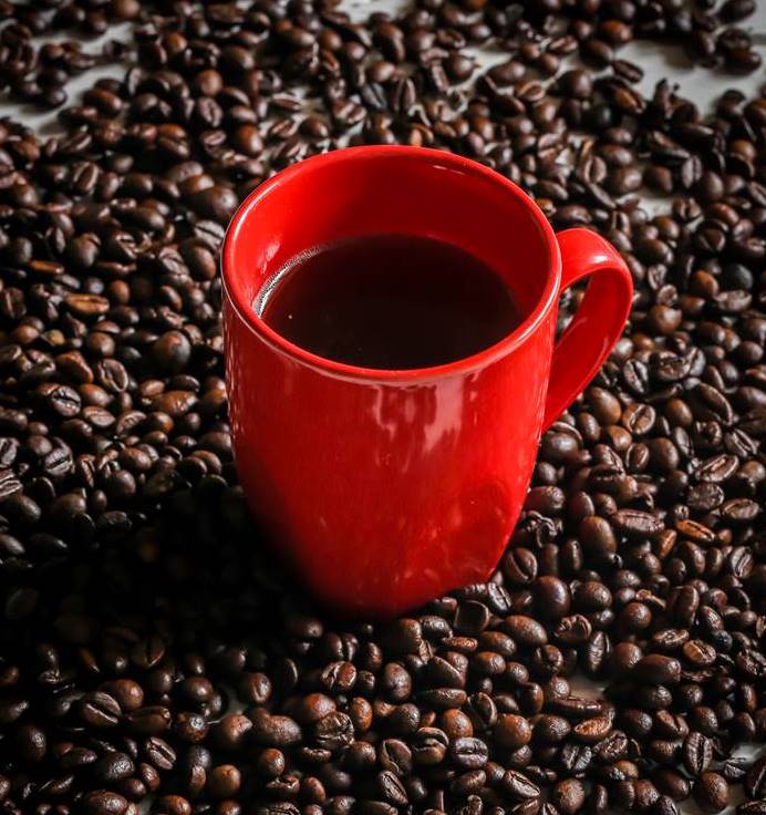 red Cup with coffee beans on wooden background