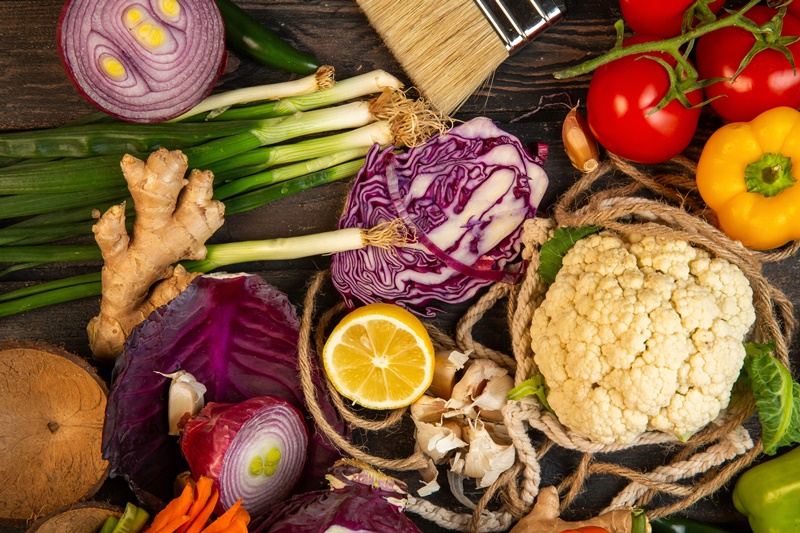 top view of various vegetables red cabbage cauliflower green onion lemon and tomatoes on on rustic background