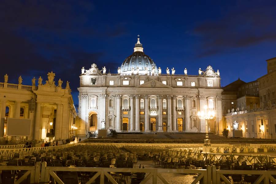 Tourism and sightseeing, night view over illuminated St. Peter's Basilica Vatican City, St. Peter's Square with benches for the event