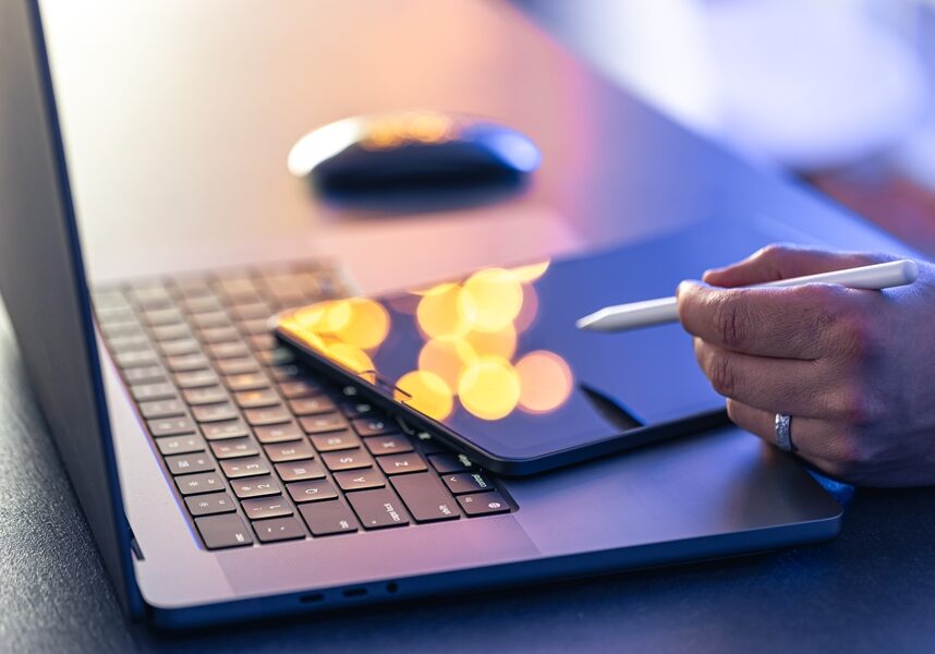 Close up of business man hand with stylus pen working on digital tablet pc and laptop on office table at home.