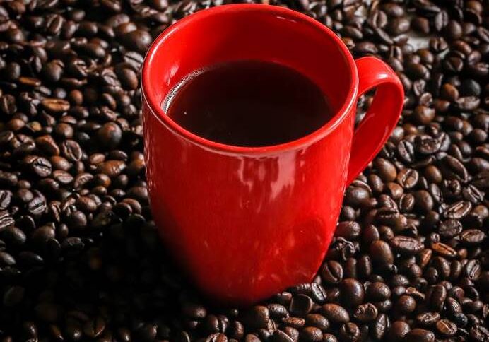 red Cup with coffee beans on wooden background