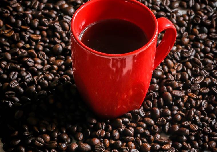 red Cup with coffee beans on wooden background