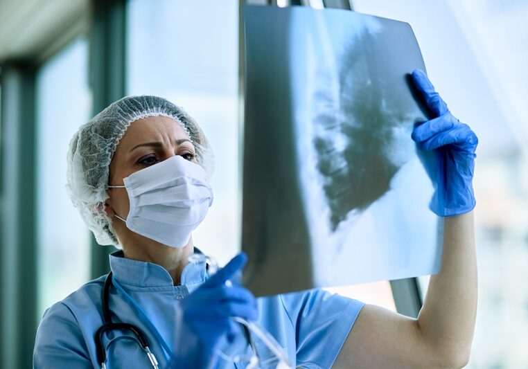 Female radiologist analyzing chest X-ray of an patient at medical clinic during coronavirus epidemic.