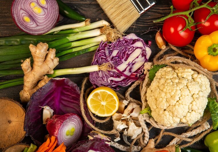 top view of various vegetables red cabbage cauliflower green onion lemon and tomatoes on on rustic background